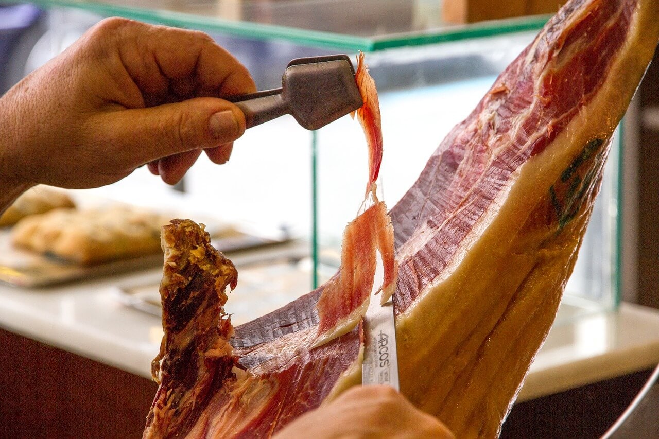 slicing off a piece of jamon