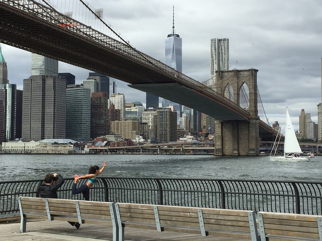 photographer taking a picture of female doing yoga in front of the brooklyn bridge 