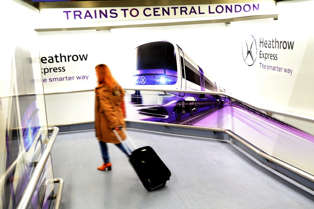 woman walking in front of heathrow express sign
