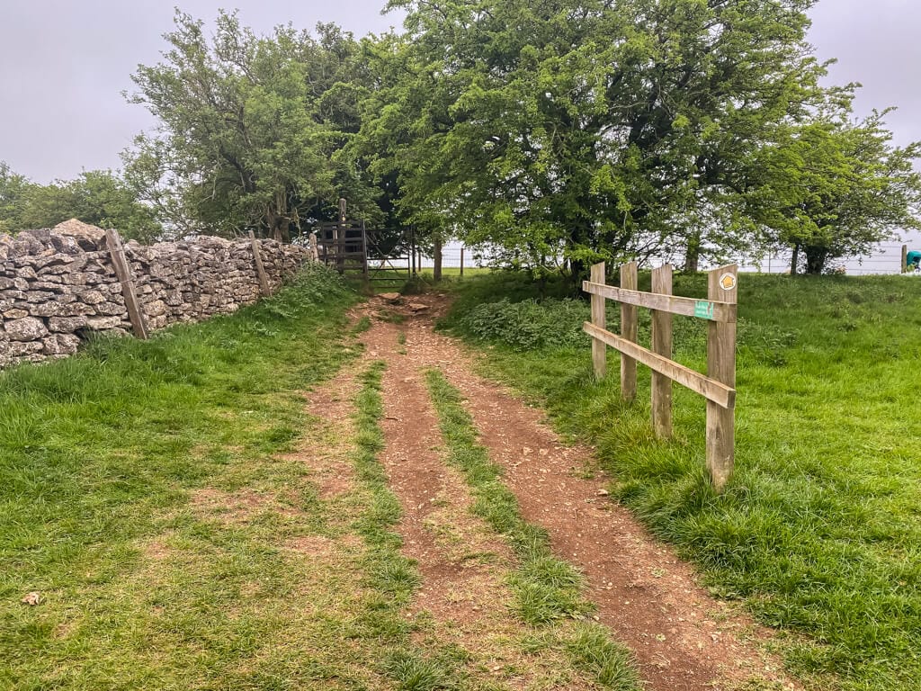 path with dry stone wall on one side and small wood fence on other side leading to gate
