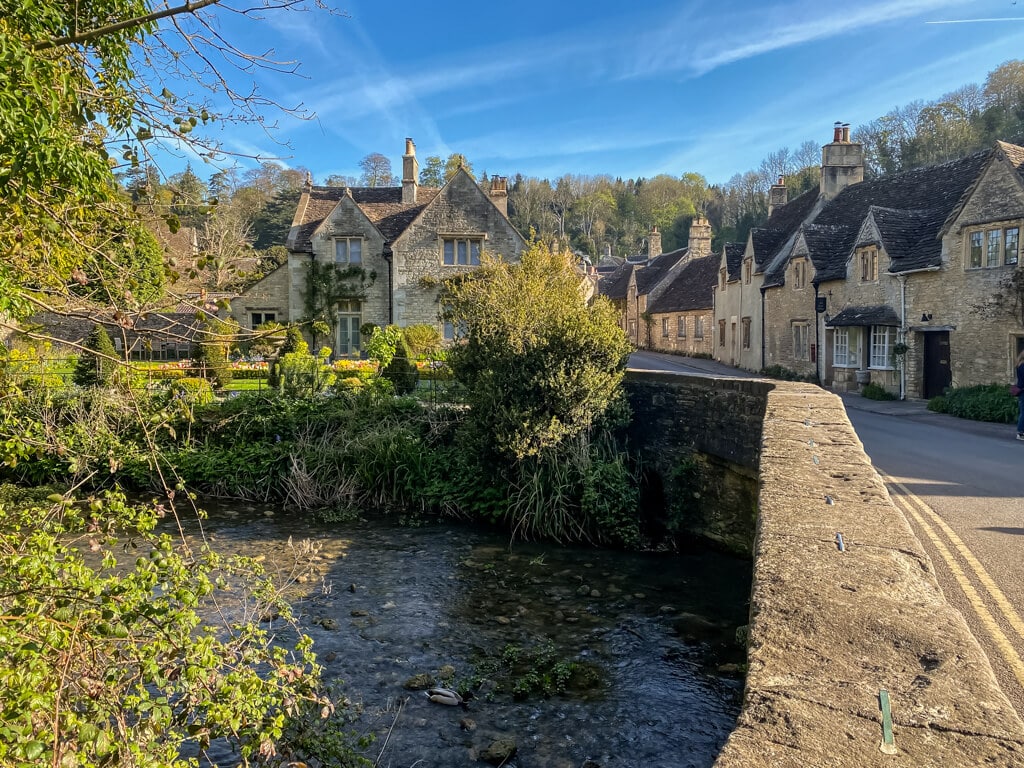 view across the bridge and stream to see the cute stone cottages of castle combe