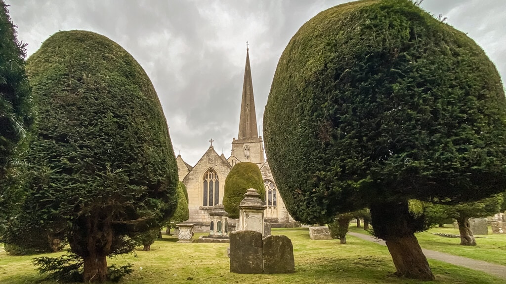 view of st marys church in painswick through the yew trees
