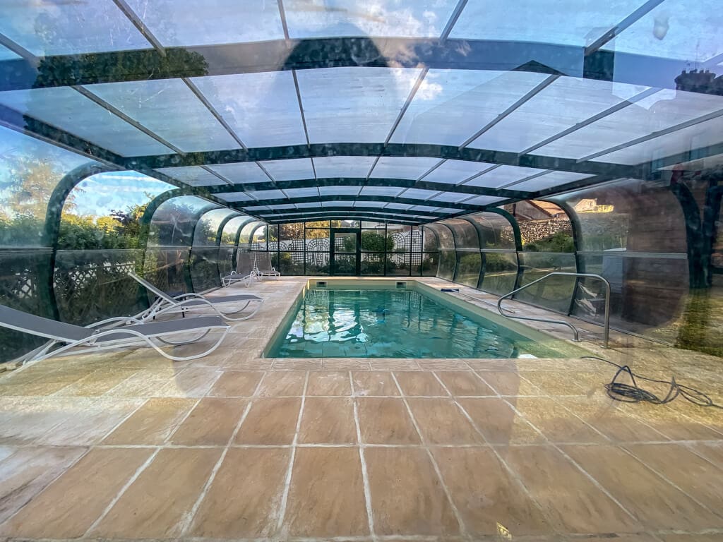 pool under a clear cover kind of like a tent with lounge chairs