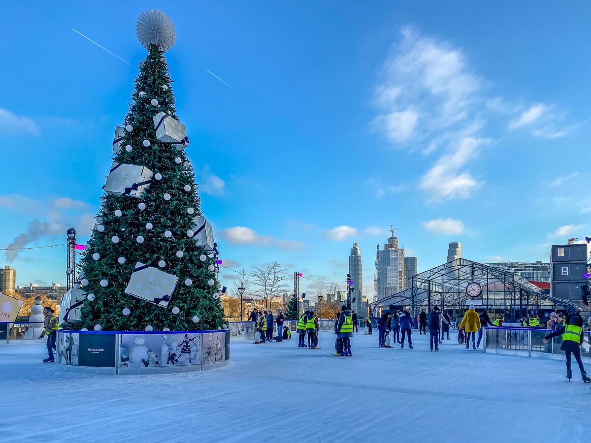ice rink with christmas tree located in front of the battersea power station