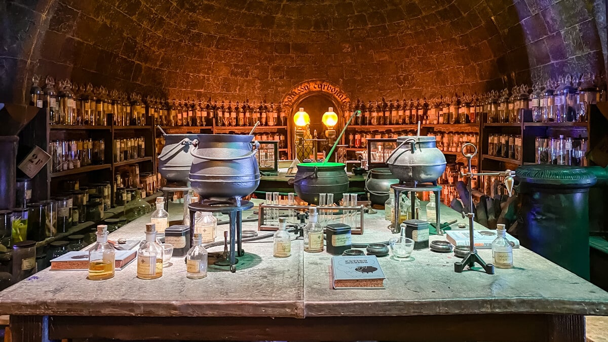 potions classroom at harry potter studios - table with pots and bottles and more bottles lining the walls