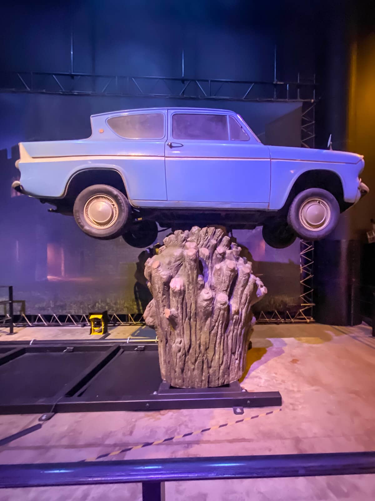 blue car on top of stump of tree at harry potter studios