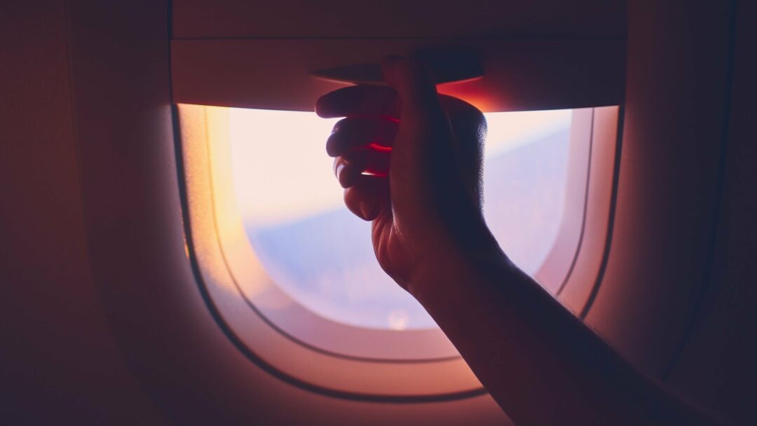 Hand pulling down or up window blinds during flight.