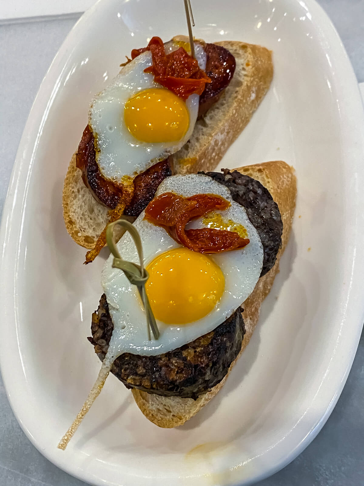 small pieces of toast with fried eggs and sausage